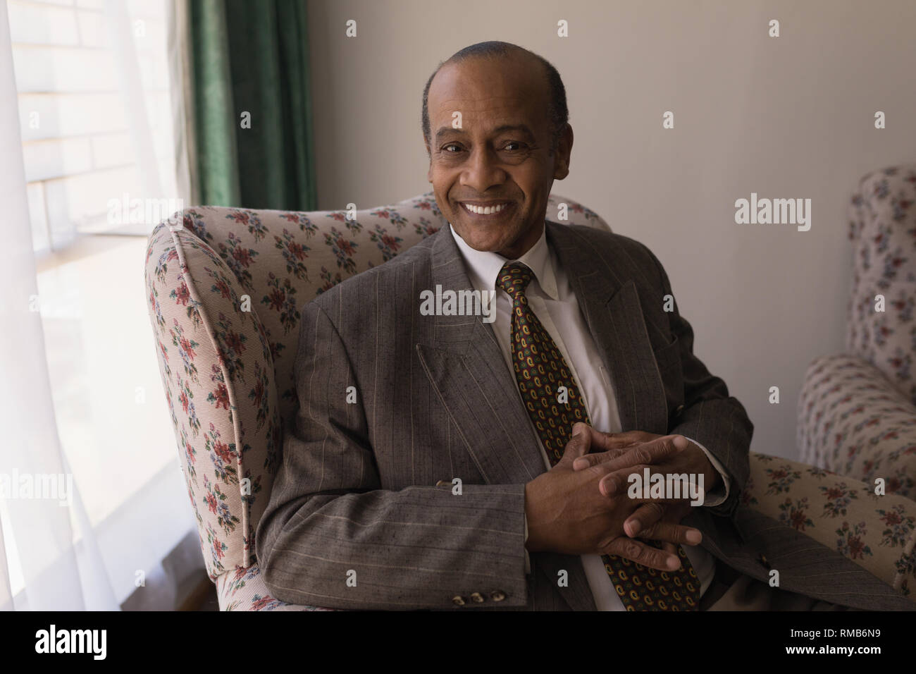 Vue avant du senior man with hand clasped looking at camera in home Banque D'Images