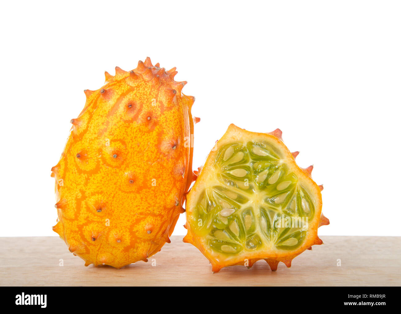 Kiwano fruit, également connu sous le nom de Cucumis metuliferus, melon à cornes, ou des cornes de l'Afrique le concombre assis sur table en bois isolé sur blanc. L'un ensemble et 1 sli Banque D'Images
