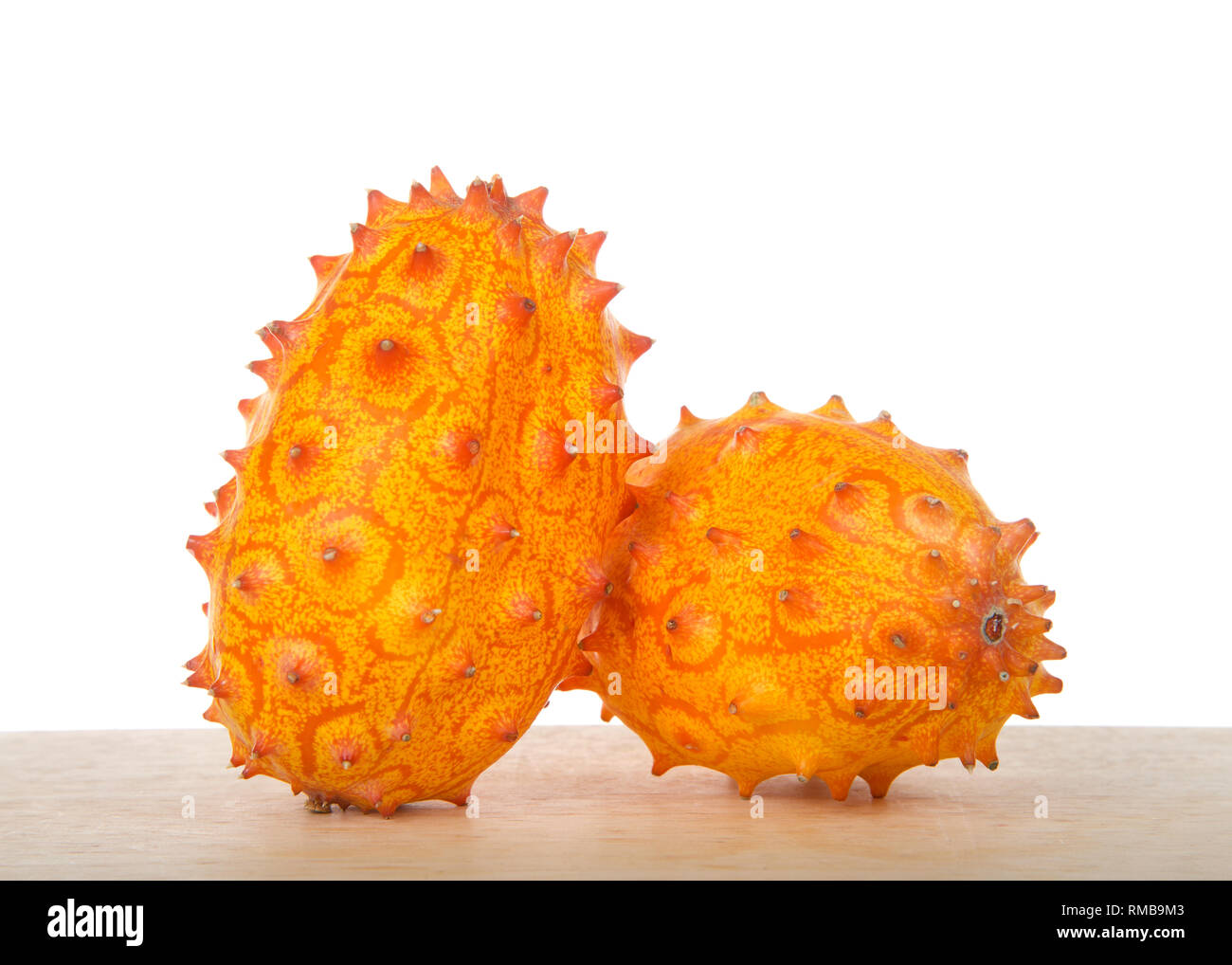 Deux ensemble Kiwano fruit, également connu sous le nom de Cucumis metuliferus, melon à cornes, ou des cornes de l'Afrique le concombre assis sur table en bois isolé sur blanc. Kiwano est Banque D'Images