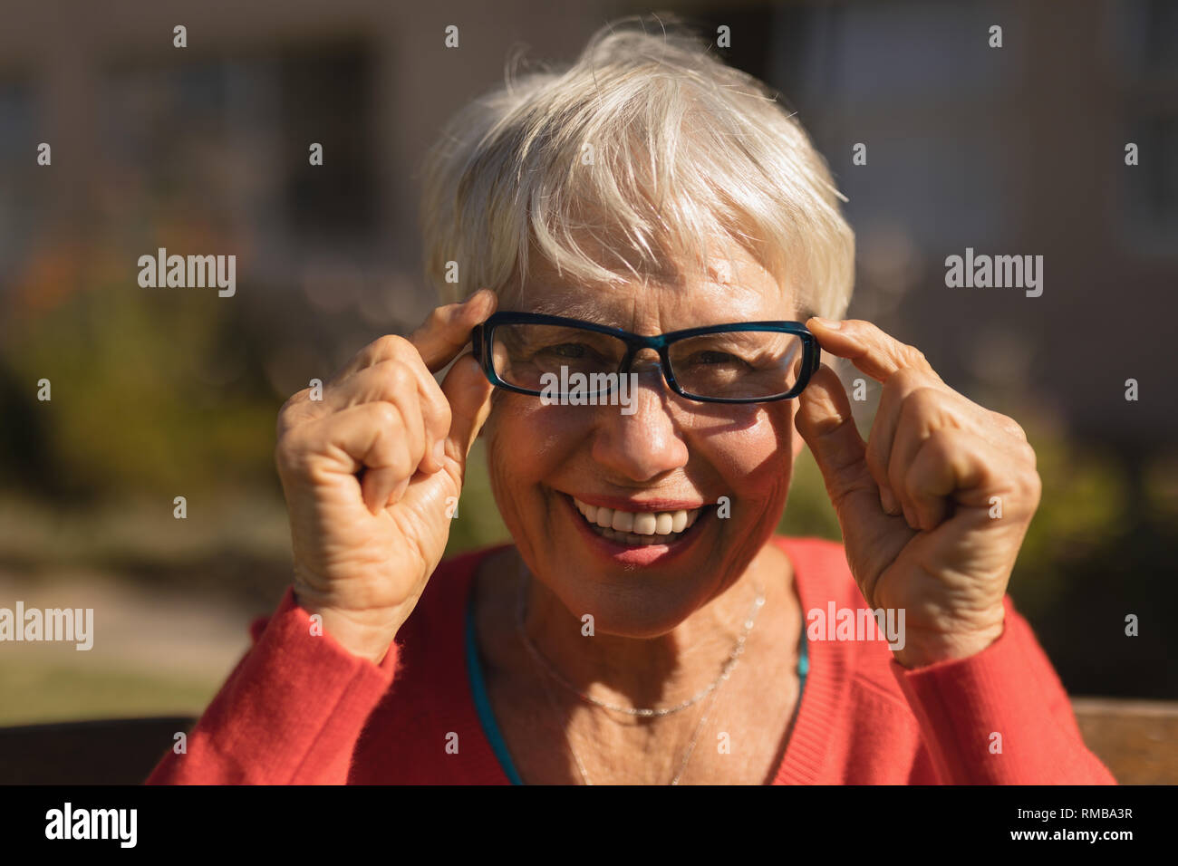 Senior woman smiling en spectacle dans le parc Banque D'Images