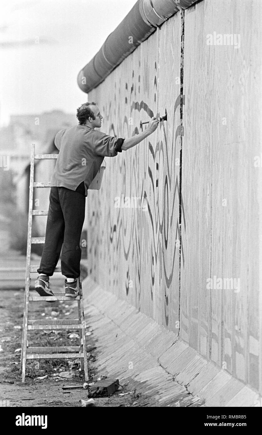 L'artiste américain Keith Haring peint 100m du mur de Berlin, près de la frontière, Ckeckpoint Charlie dans le quartier de Kreuzberg. Banque D'Images