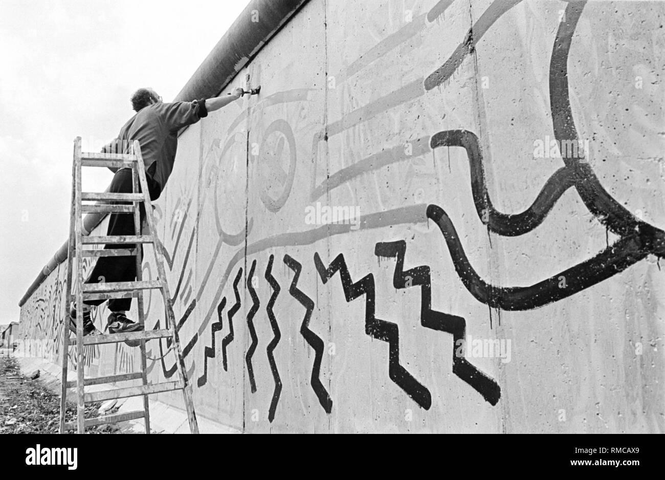 L'artiste américain Keith Haring peint à 100 mètres du mur de Berlin, près de la frontière, Ckeckpoint Charlie dans le quartier de Kreuzberg Banque D'Images