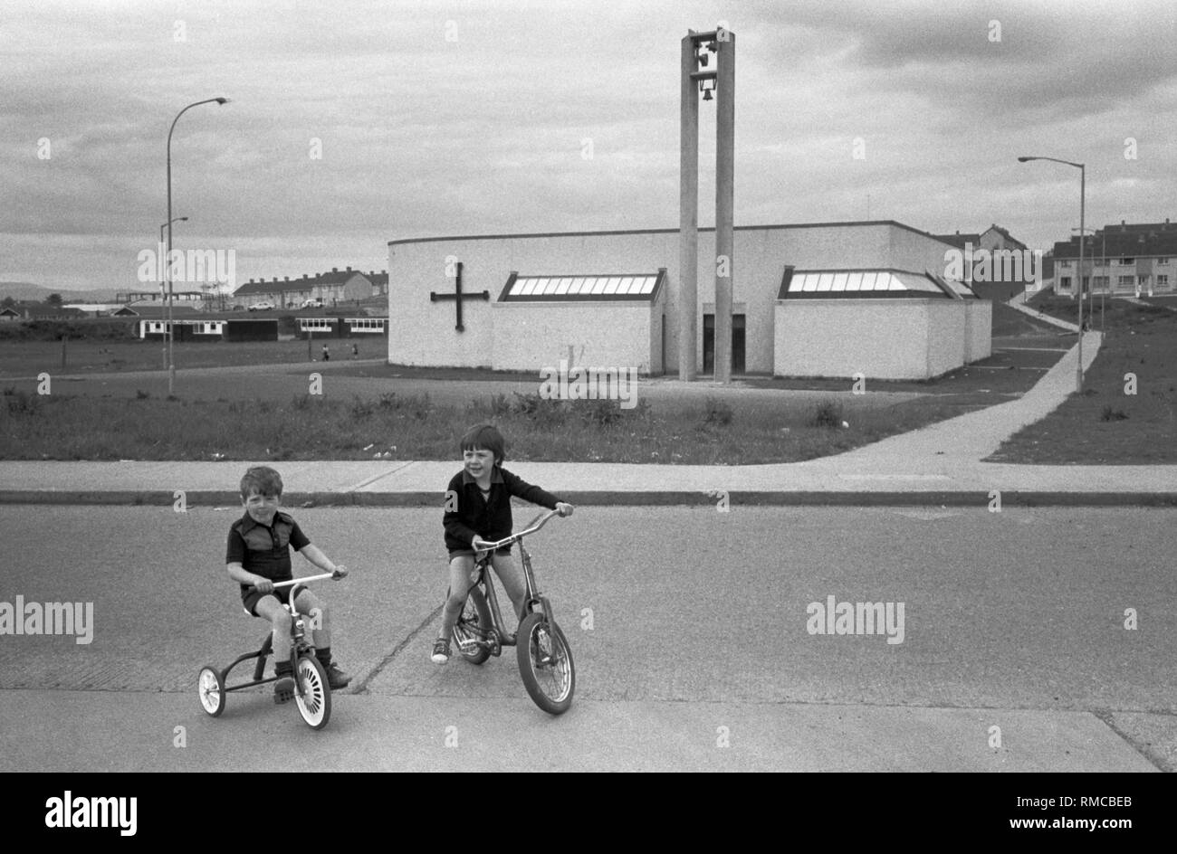 1970s enfants irlandais jouant dehors sur leurs vélos. Limerick, dans le comté de Limerick, Eire. Côte ouest de l'Irlande du Sud 70s. La nouvelle église de la Sainte famille a été construite dans le parc O'Malley, dans la partie Limerick du domaine de Southill. HOMER SYKES. Banque D'Images