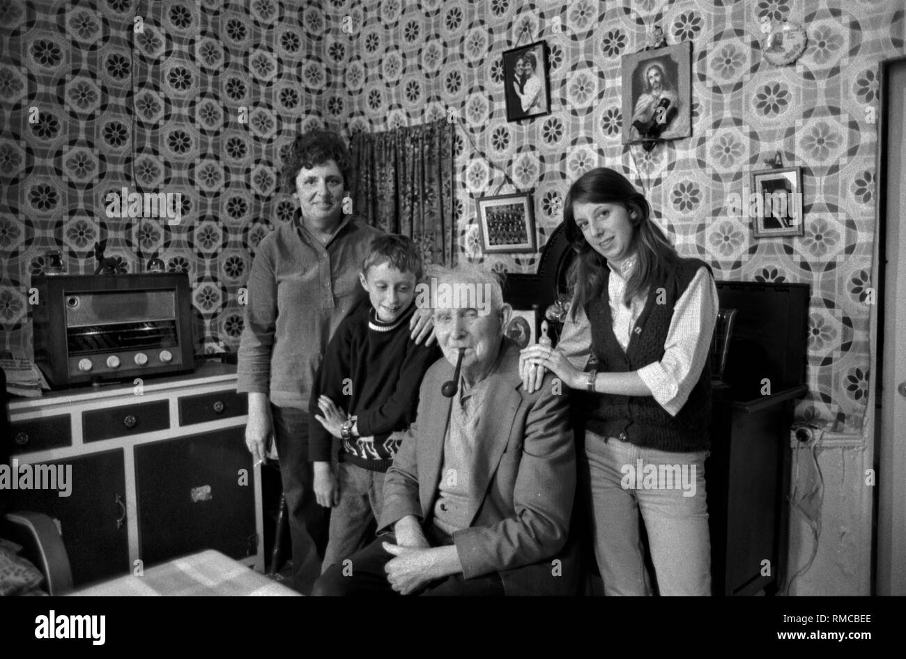 Portrait de famille irlandaise des années 1970 de trois générations à l'intérieur de la maison familiale. Limerick, dans le comté de Limerick Eire. Côte ouest de l'Irlande du Sud. La famille Storan à Brennans Row Limerick. Joe a 80 ans et a vécu ici dans ce chalet à deux pièces tout est vie, il n'y a pas d'eau chaude. 1979. HOMER SYKES Banque D'Images