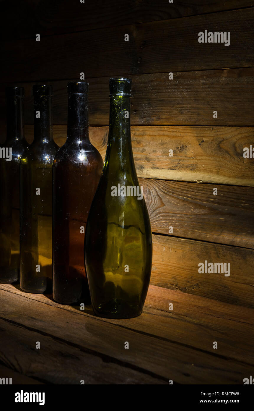 Vieilles bouteilles de vin dans le noir sur une table en bois. Banque D'Images