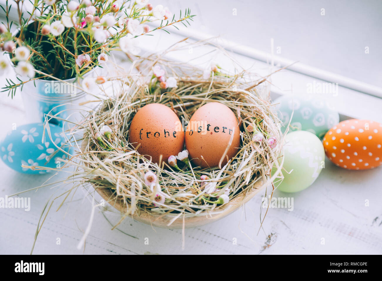 Les oeufs de Pâques avec des timbres en caoutchouc 'Frohe Ostern" message d'un texte dans un nid de foin et de fleurs à côté d'une fenêtre à la maison Banque D'Images