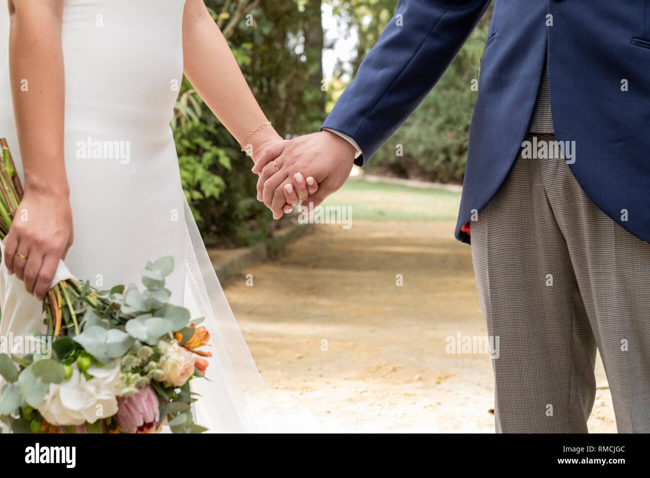 Couple in love se serrer la main, elle avec bouquet de fleurs Banque D'Images