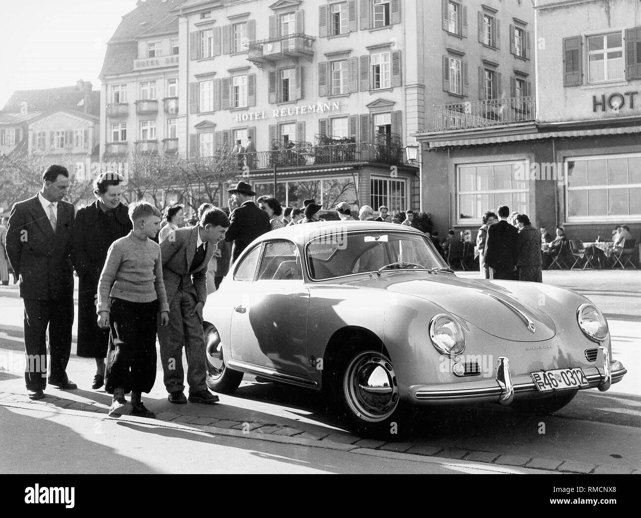 Scène de rue à Lindau : enfants, regardez curieusement à travers les fenêtres d'une Porsche. Banque D'Images