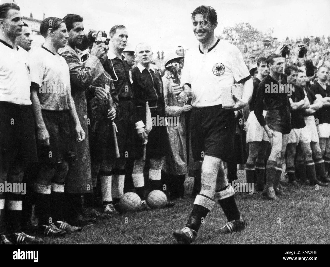 Après avoir remporté la finale de la Coupe du Monde FIFA 1954, le capitaine de l'équipe nationale allemande victorieuse, Fritz Walter promenades smiling passé les autres joueurs et juges de ligne avec le trophée. Banque D'Images