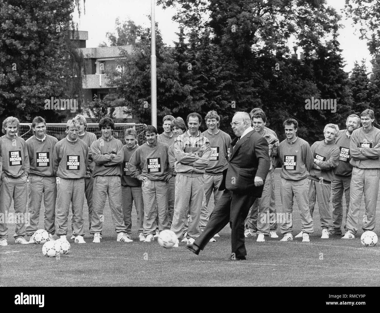 Le chancelier allemand Helmut Kohl (milieu) kicks a football lors de sa visite du camp d'entraînement à Kaiserau, où l'équipe nationale allemande séjours. Banque D'Images