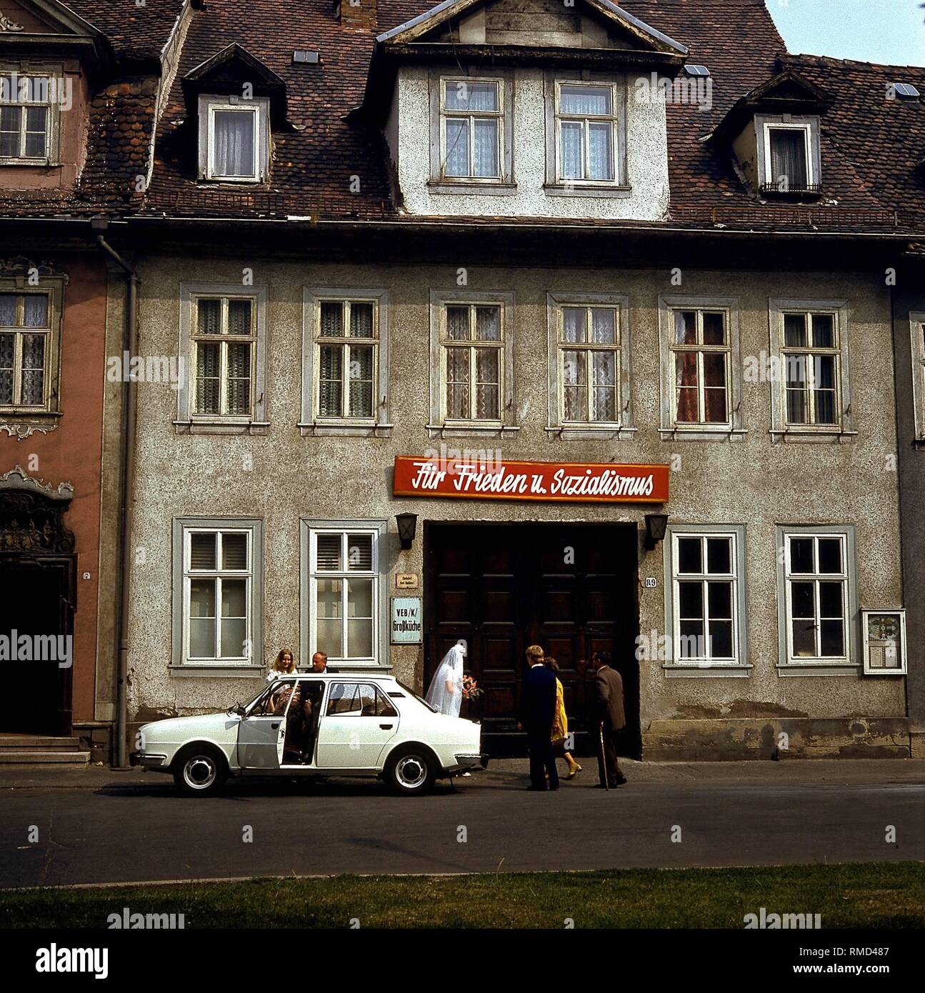 Une femme et un homme en face de l'office d'Erfurt. Au-dessus de la porte le slogan "pour la paix et le socialisme". Banque D'Images