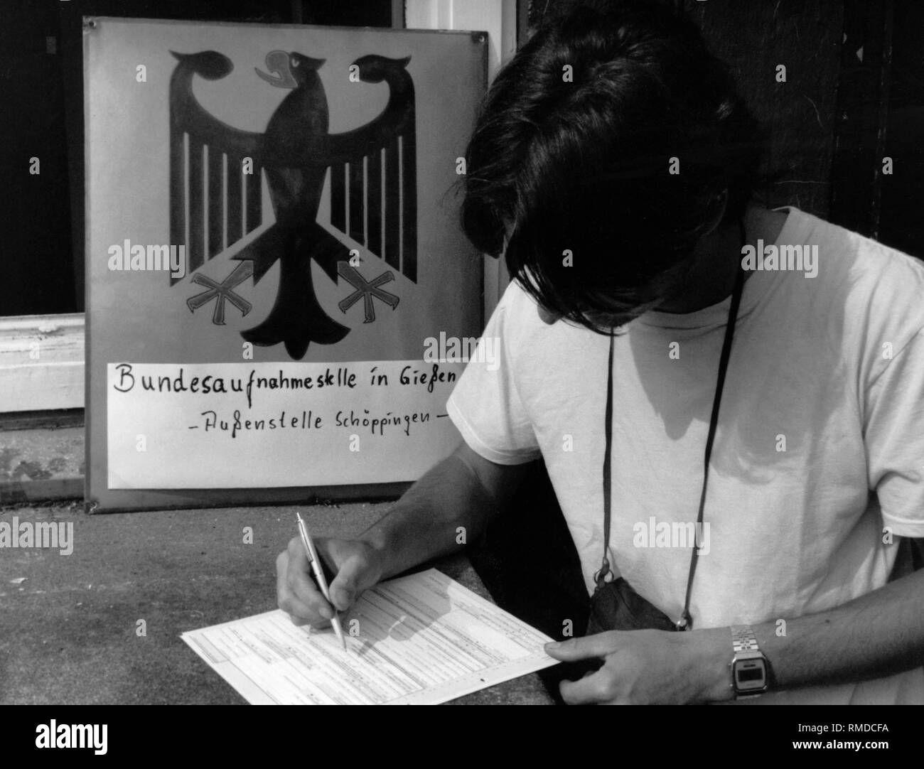Un jeune homme, qui a fui par la Hongrie de la RDA, remplit une demande d'admission dans le camp de réfugiés de Schoeppingen. Banque D'Images