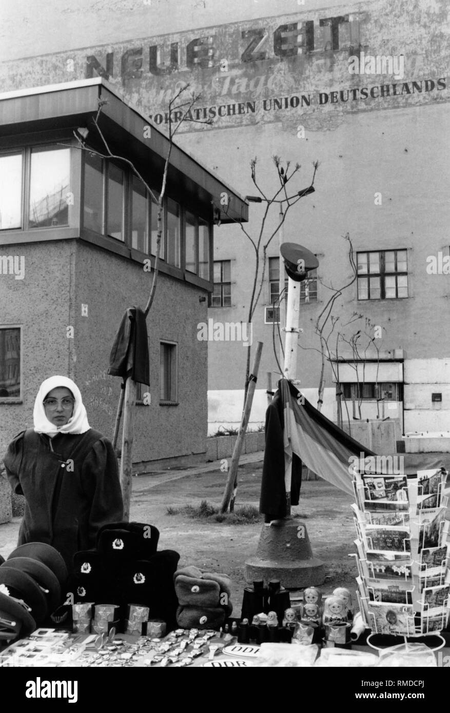 Une femme turque vend des pièces de voiture, des signes, des médailles et des cartes postales de la RDA comme souvenir à l'ancien poste-frontière Checkpoint Charlie. Au-dessus d'un lettrage de la "neue Zeit", le journal du parti est de la CDU. Banque D'Images