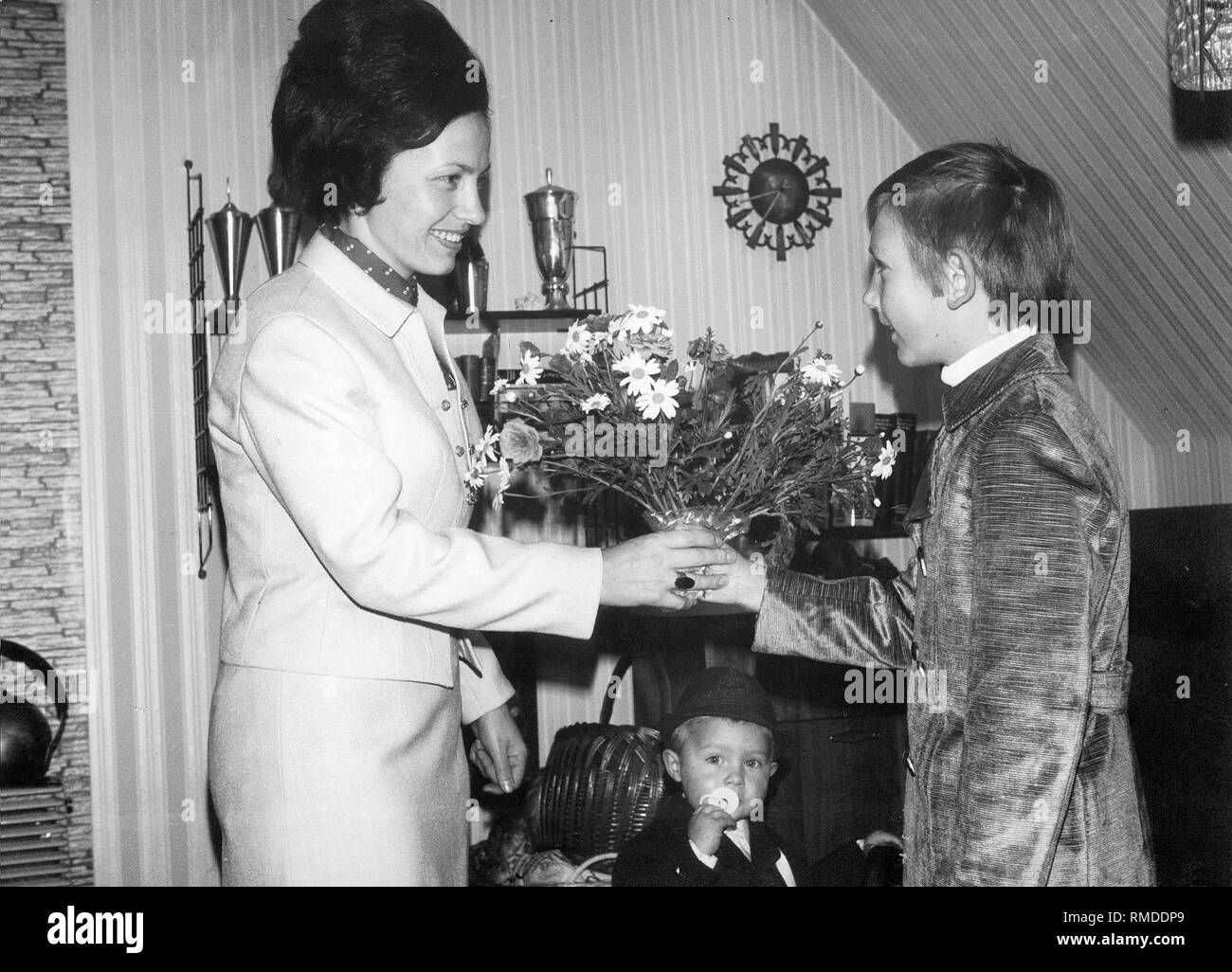 Une mère reçoit un bouquet de fleurs de son fils le jour de la mère. Banque D'Images