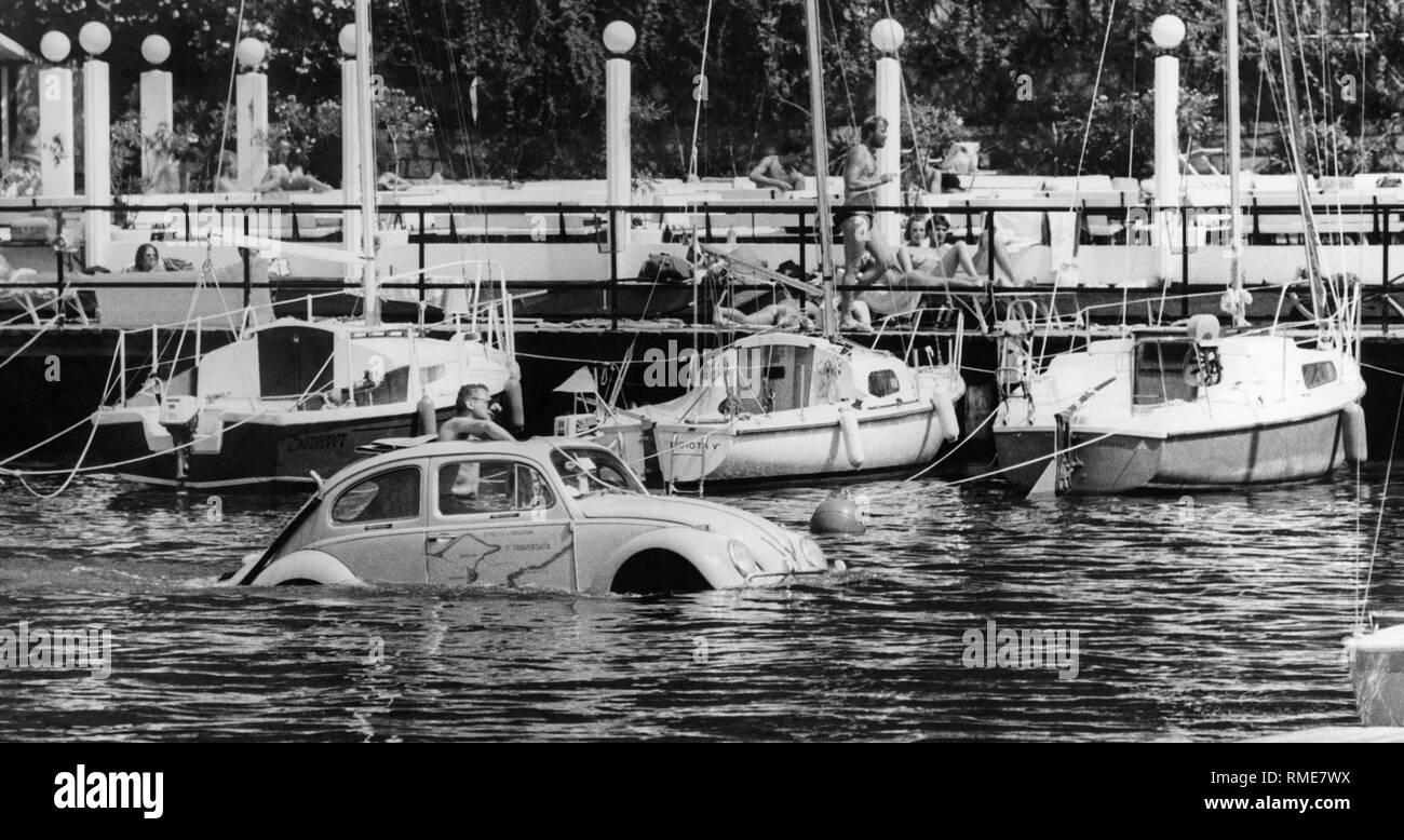 Une VW Beetle flottant en face de la jetée d'atterrissage dans la marina de Torbole sur le lac de Garde. Banque D'Images