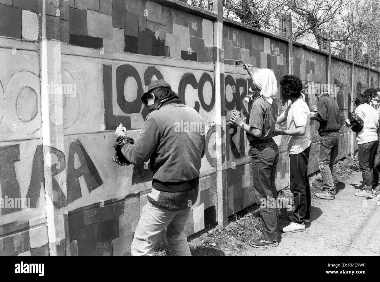 Les membres masqués de la brigade de la jeunesse communiste 'Ramona Parra' peindre les murs avec des slogans lors d'un rassemblement de l'opposition au Chili. Banque D'Images