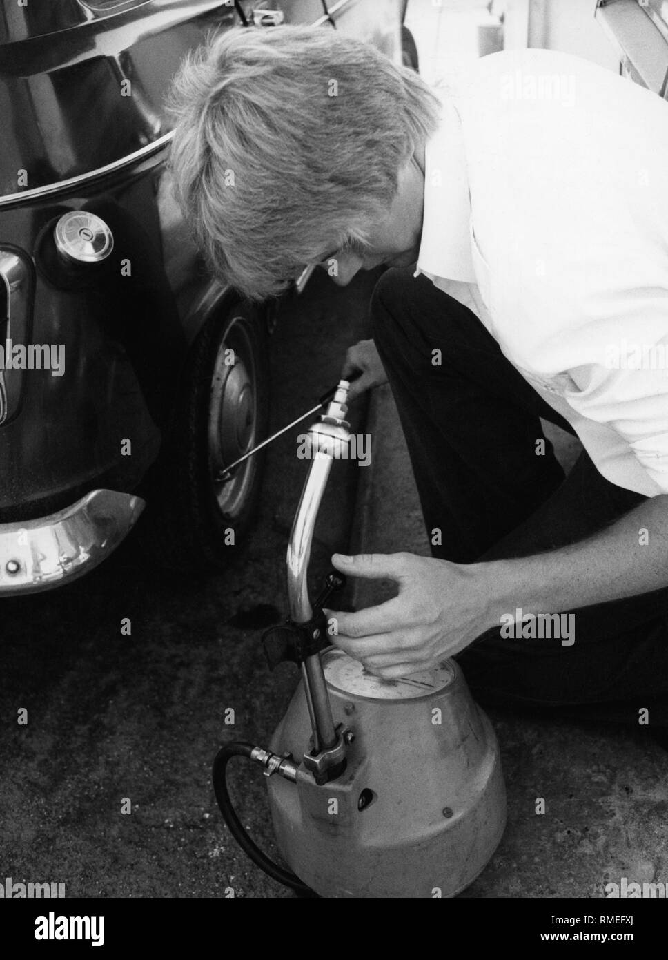 Un homme mesure la pression des pneus d'une Renault R4. Banque D'Images