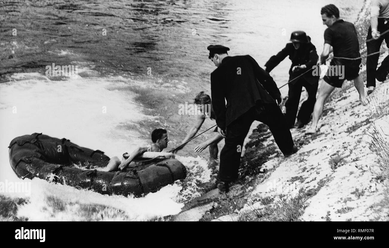 Les hommes secourir un homme sur un radeau de caoutchouc à l'Isar, à propos de 1958. Banque D'Images