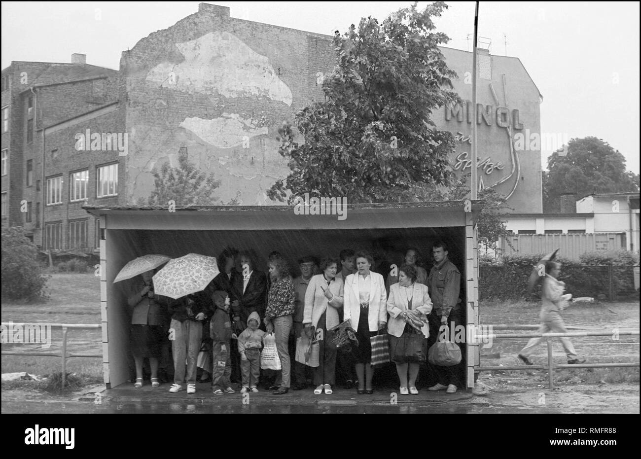 Allemagne, Berlin, 29 mai 1990 : arrêt de tramway, l'attente, l'attente (RDA) les citoyens à l'abri de la pluie (refuge), publicité (RDA) : 'Minol zur Spitze', Weissensee, Berlin. Banque D'Images