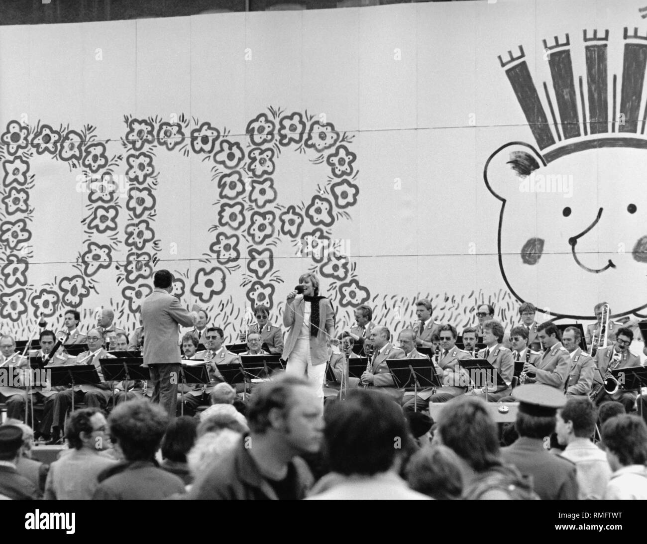 Le Parti socialiste unifié d'Allemagne (SED) et la population de célébrer 35 années d'existence de la RDA avec le district de festivals, comme ici, à l'Alexanderplatz. Dans l'animation, cependant, l'on cherche à imiter l'Occident. Sur scène est un chanteur et de la musique avec orchestre orchestre. Sur le mur un lettrage de la RDA à partir de fleurs et d'un anniversaire enfant. Banque D'Images