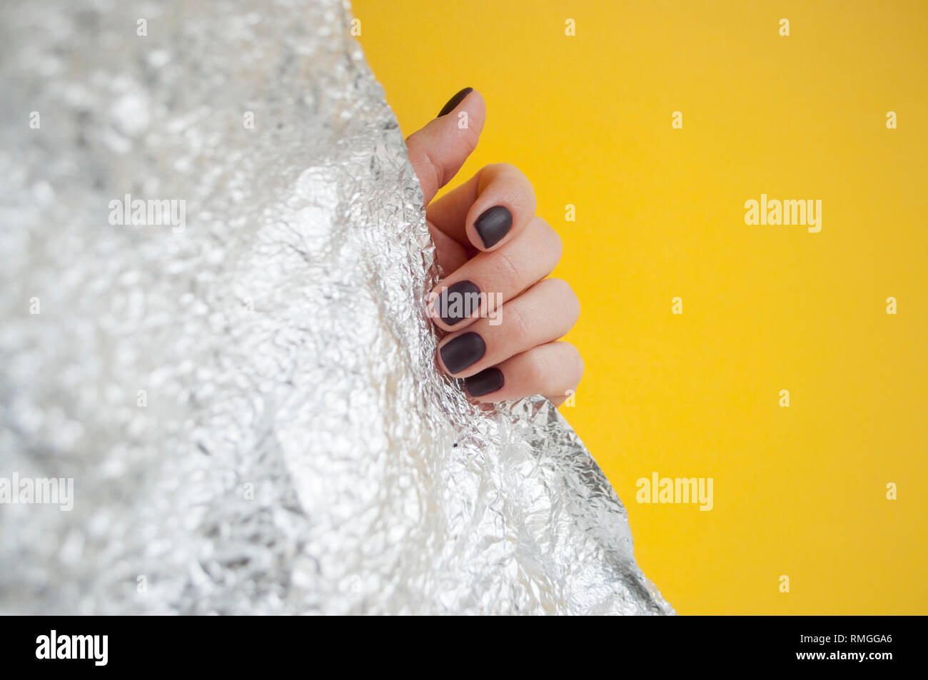 La main de la jeune femme avec une belle manucure sur fond jaune et brillant métallique avec copyspace. Banque D'Images