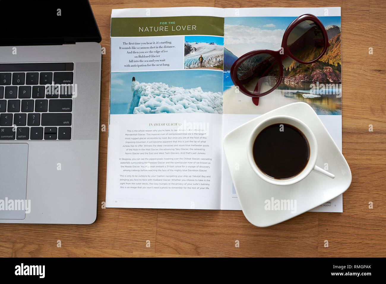 Article dans un journal de voyage - de la planification et de nouvelle aventure en Alaska. Le café, des lunettes, de la brochure et de l'ordinateur portable sur une table en bois. Banque D'Images