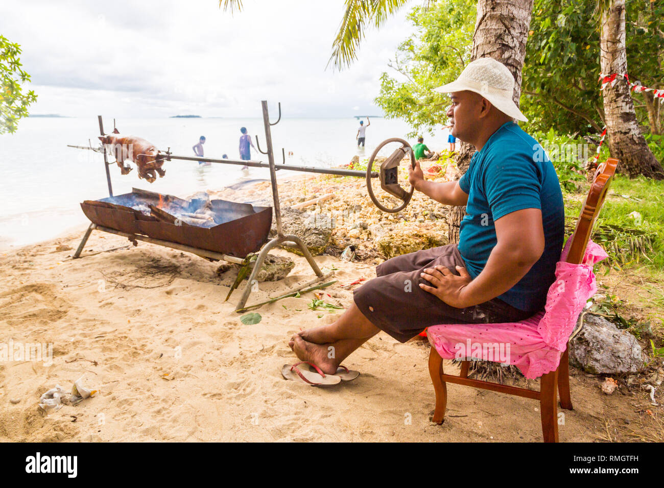 L'île de Tongatapu (Tonga) - 10/01/2014 : un homme autochtone autochtone locale n'porc polynésien un barbecue d'un petit porcelet sur un feu ouvert d'une grill m Banque D'Images