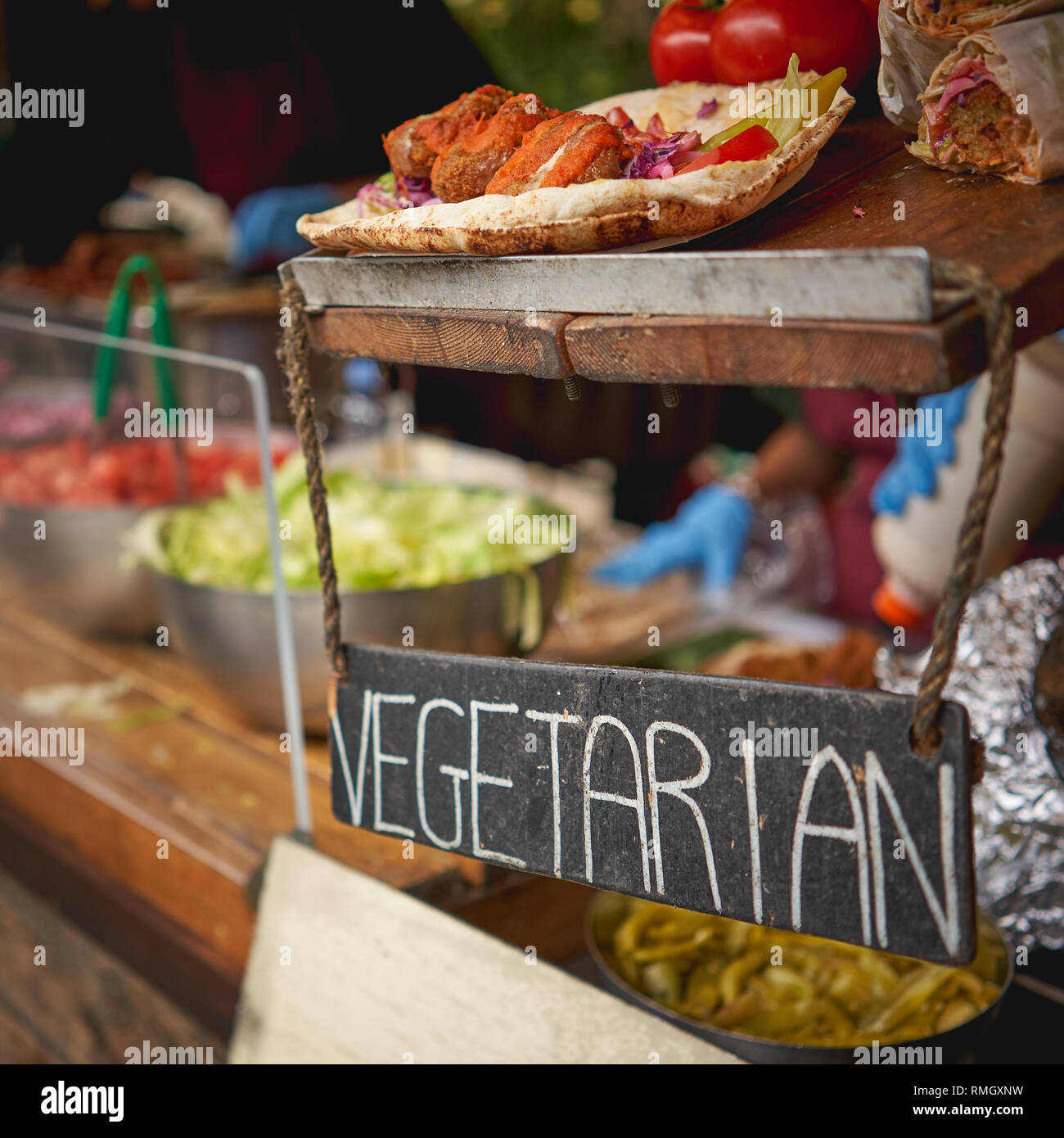 Falafel végétarien avec des sauces et de pain avec un végétarien hanging panneau en bois à un street food dans un marché local. Format carré. Banque D'Images