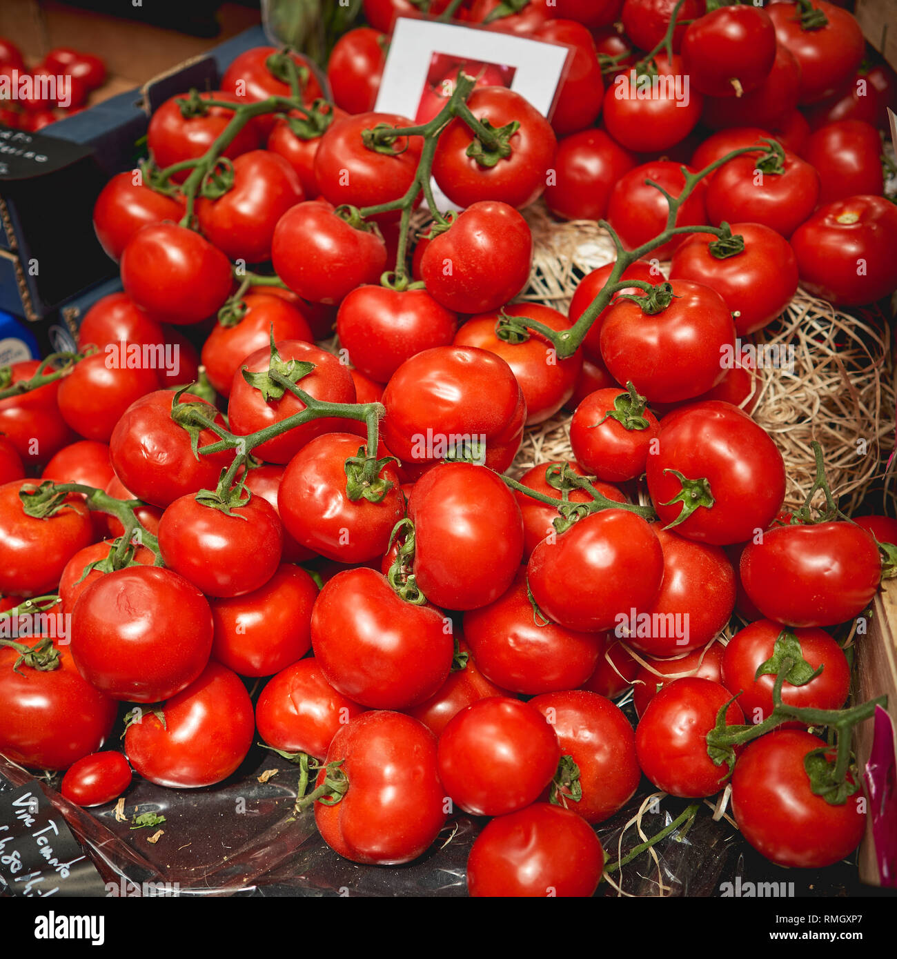 Un rouge bio tomates sur la vigne dans des paniers en bois en vente sur un étal de marché fermier local. Format carré. Banque D'Images