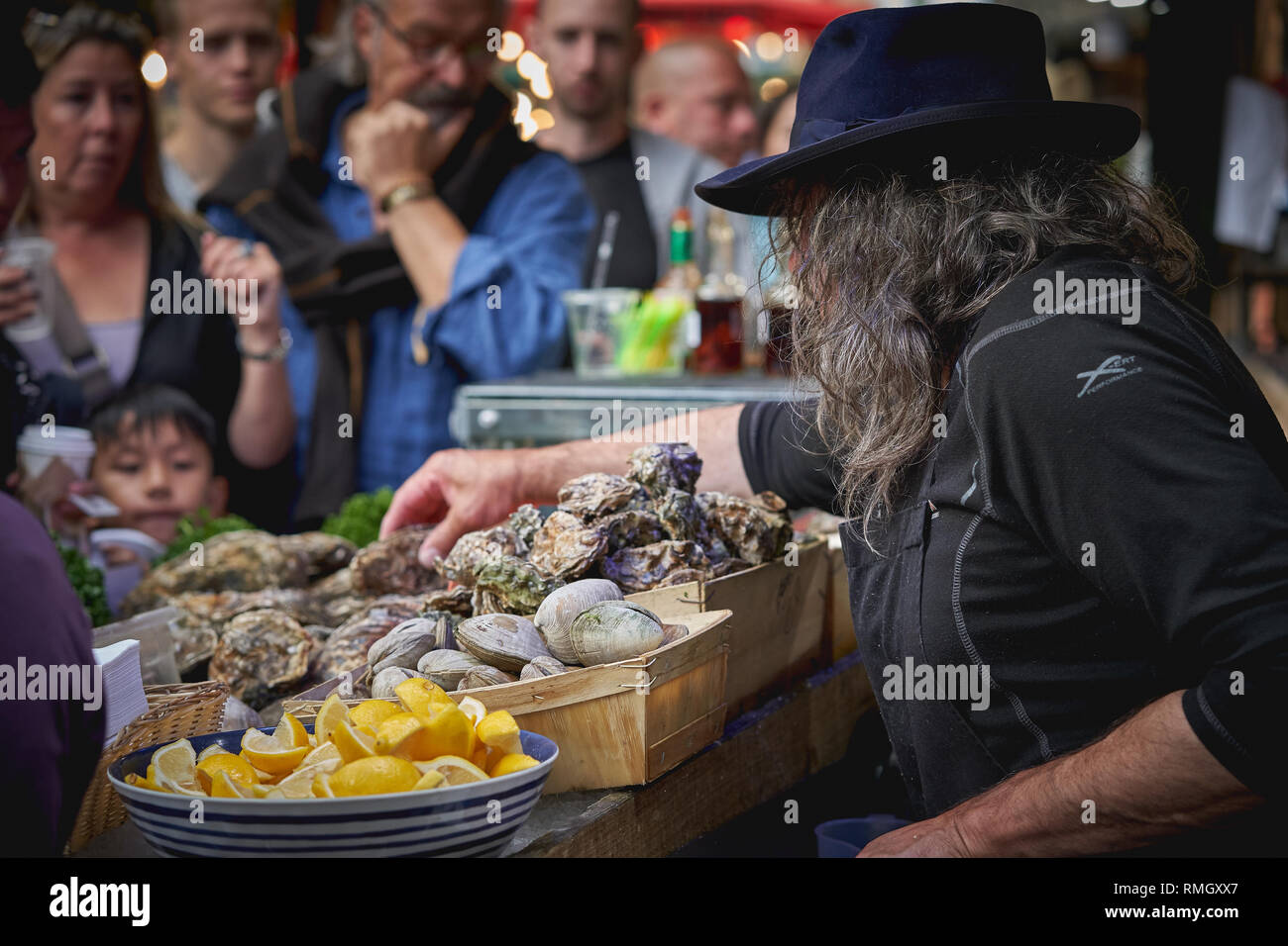 Londres, Royaume-Uni - juin 2018. Un poissonnier vend calage les huîtres crues et les crustacés en Borough Market, l'un des plus grand et le plus ancien marché alimentaire de Londres. Banque D'Images