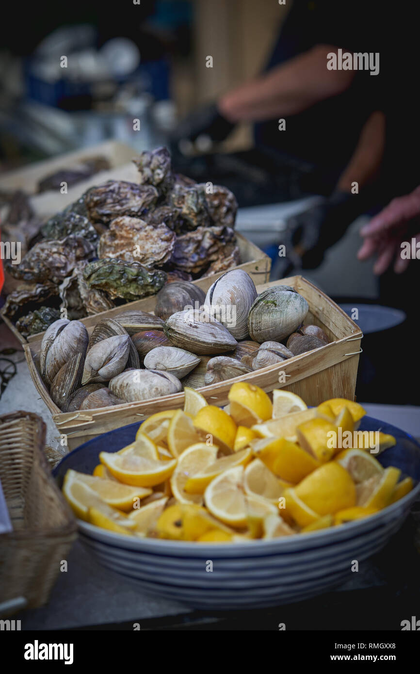 Les huîtres crues et les fruits à la vente à un décrochage poissonnier dans un marché local. Le format Portrait. Banque D'Images