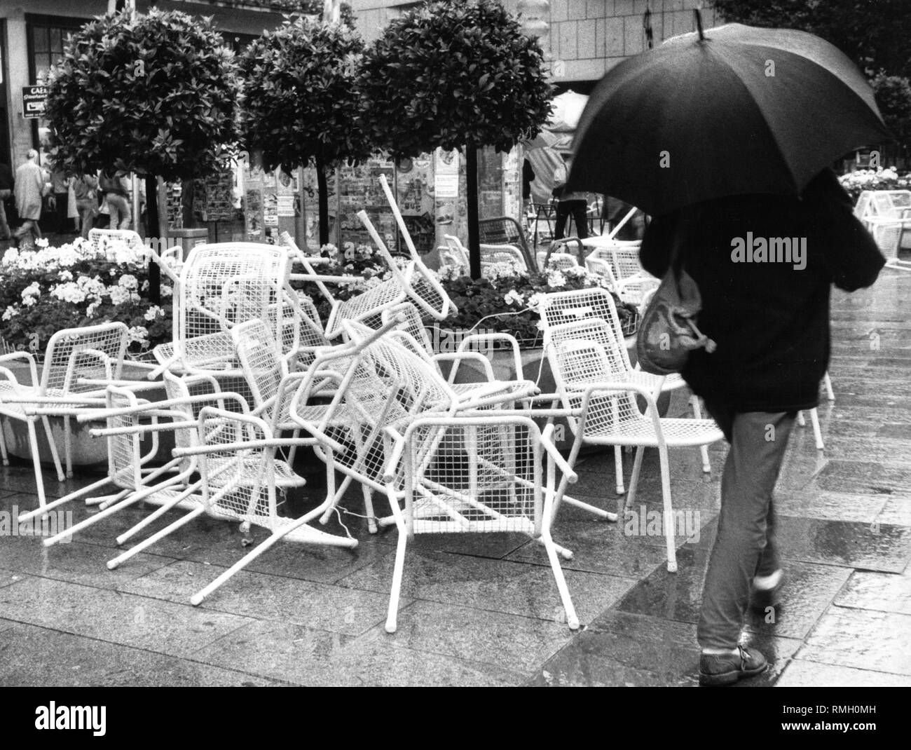 Des chaises, une douche et un homme avec un parapluie sur la Marienplatz à Munich. Banque D'Images