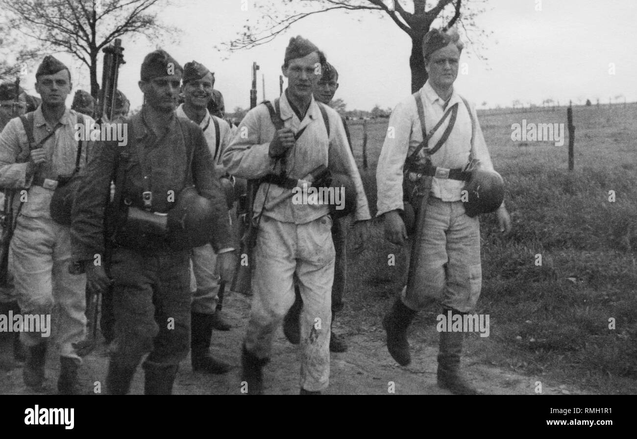 Un groupe de sous-officiers de la Luftwaffe pendant la marche d'un exercice  sur le terrain. Le deuxième soldat de la gauche porte un MG-13, sur la  droite le deuxième tir, qui effectue