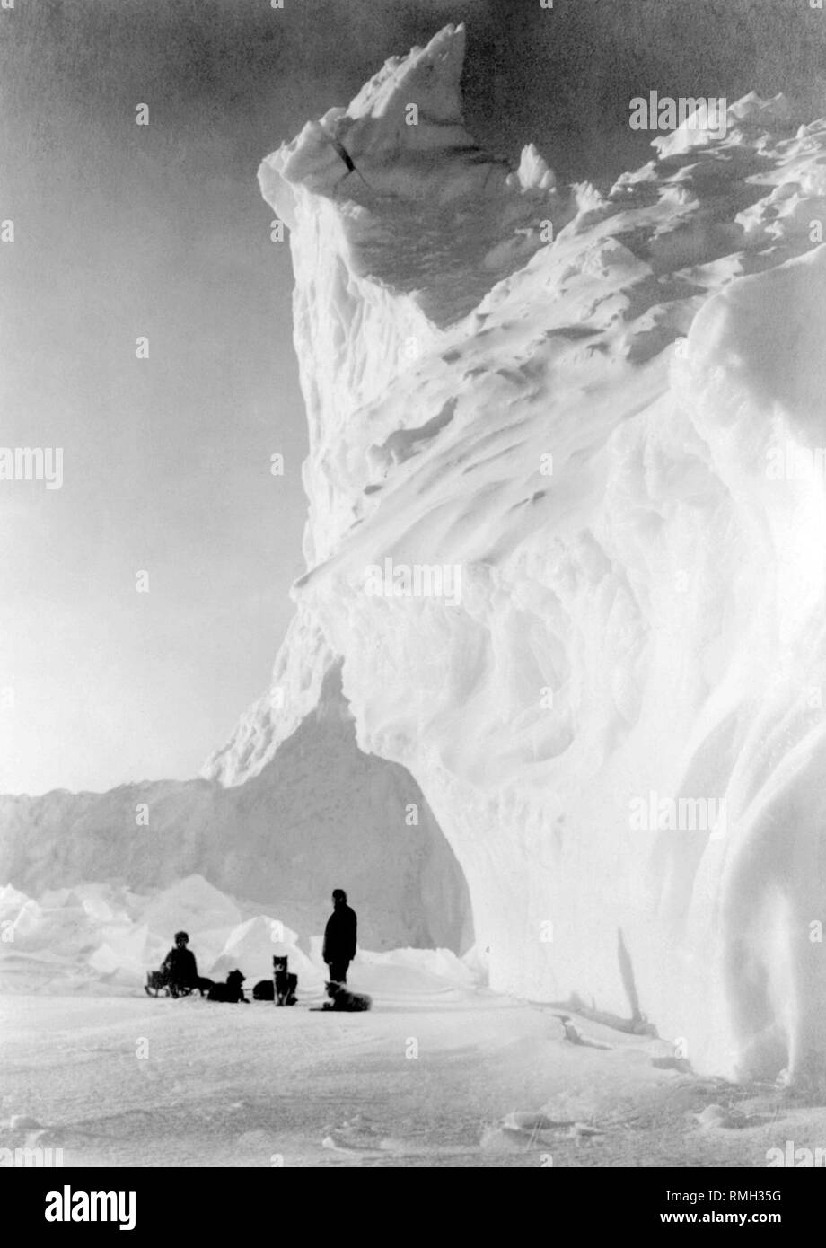L'équipe de chien de deux hommes et les chiens se reposant près d'un iceberg sur l'expédition Terra Nova au cours de l'expédition Antarctique Britannique en Antarctique Photo prise 1910 Banque D'Images