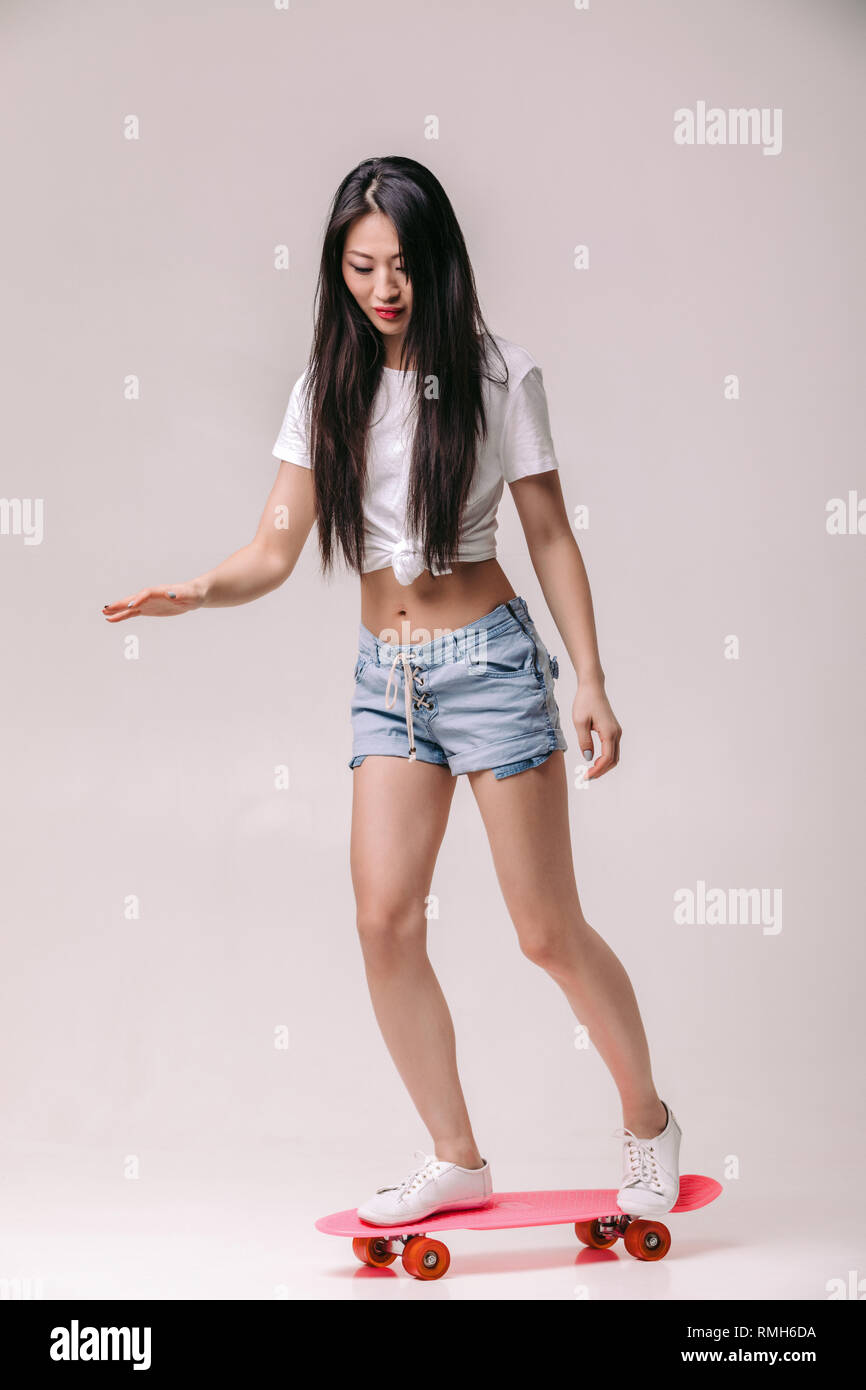 Belle jeune femme asiatique en shorts avec skateboard Banque D'Images