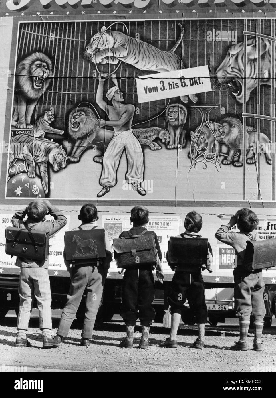 Les élèves avec leurs cartables admirer l'affiche de cirque Althoff' annonçant sa visite, photo des années 50. Banque D'Images