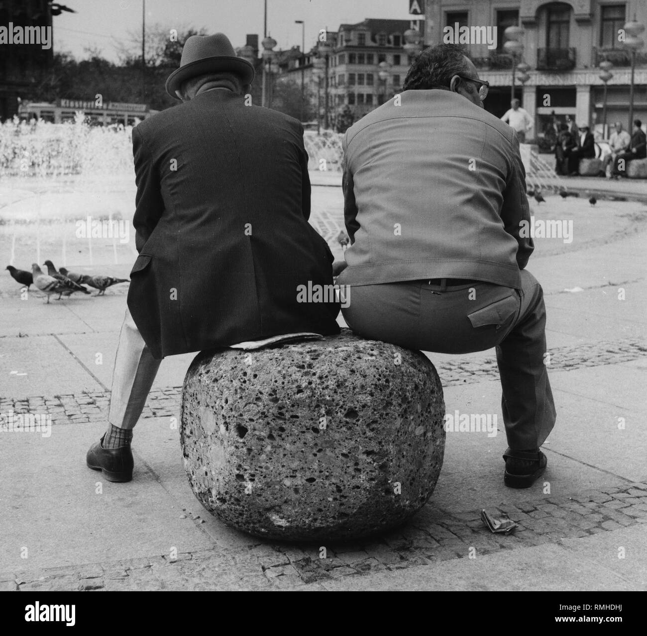 Deux hommes assis sur une pierre en face de la fontaine à la Stachus à Munich. Banque D'Images