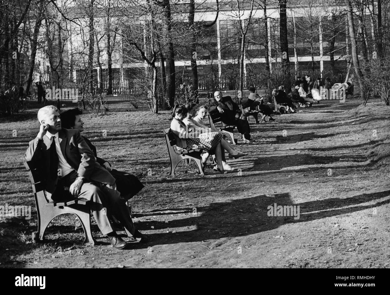 Les gens profiter du soleil sur des bancs au Jardin Anglais de Munich. Banque D'Images