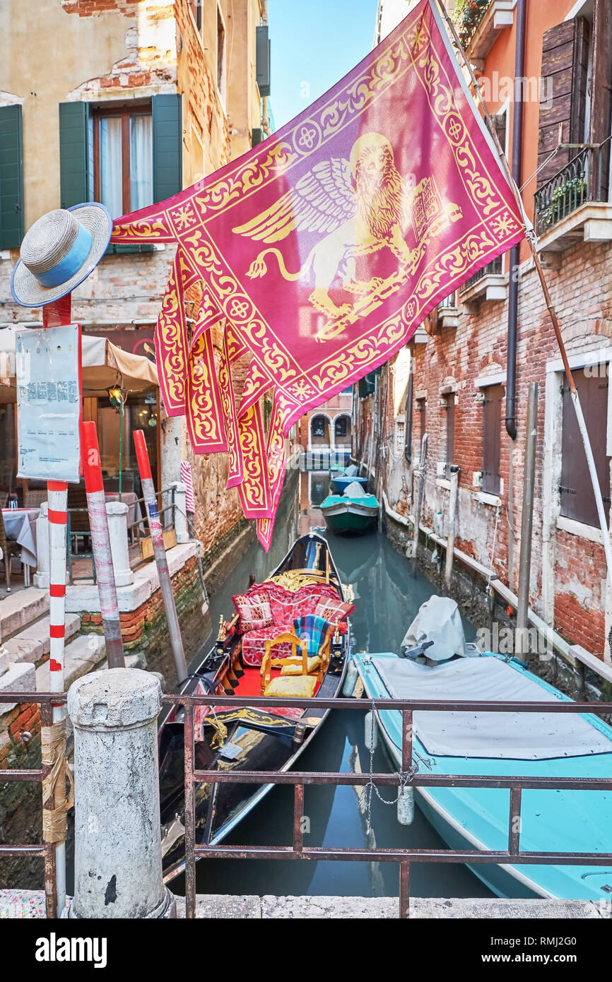 Gondola, voile et le drapeau de la région italienne de la Vénétie sur le  canal à Venise à l'Italie, la station de télécabine. Le Gondolier  traditionnel chapeau de paille sur un po