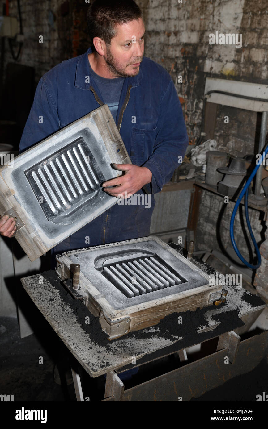 Un fondeur rappelle le canal par lequel le fer fondu s'écoule pour faire un feu de foyer en fonte. Banque D'Images