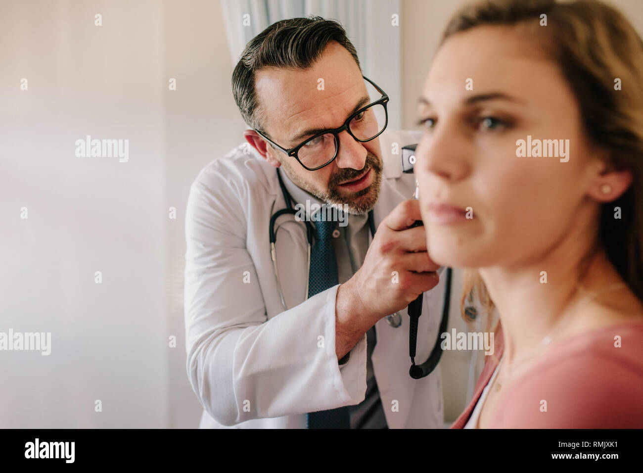 Médecin ORL à la femme dans l'oreille du patient avec un instrument. Doctor examining patient's ear avec otoscope dans sa clinique. Banque D'Images