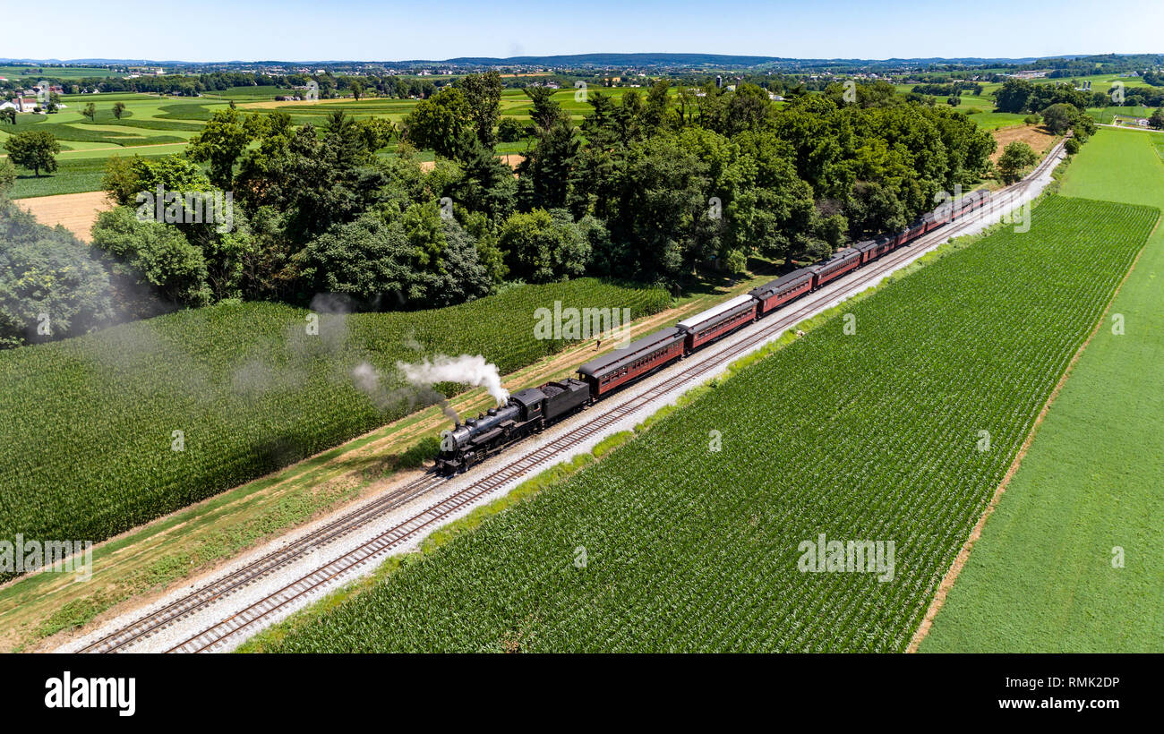 Vue aérienne d'un train de voyageurs à vapeur que quelques bouffées de fumée dans la campagne Amish sur une journée de printemps ensoleillée Banque D'Images