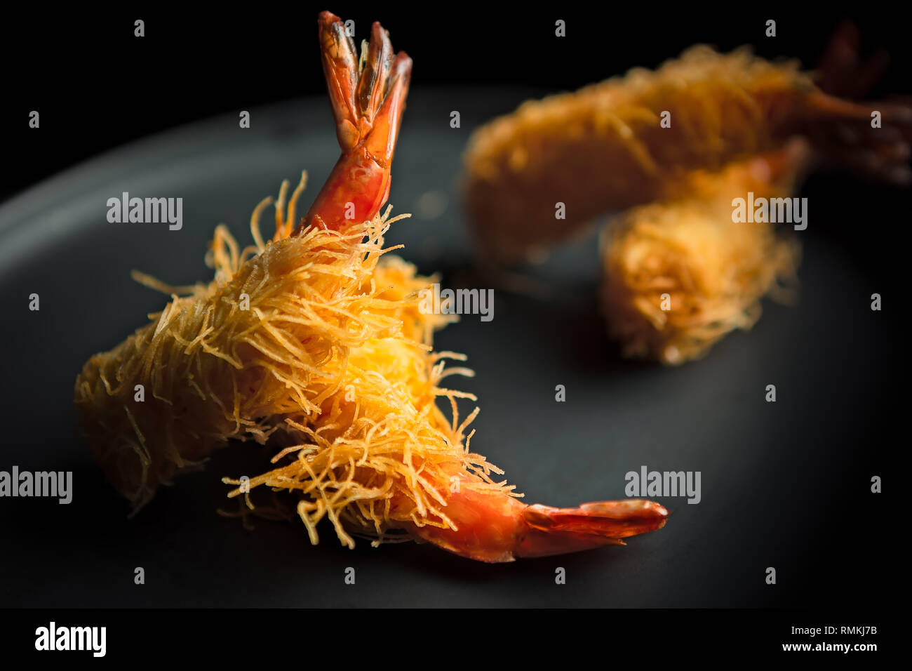 Quatre crevettes de style tempura japonais servies sur une assiette grise comme démarreur Banque D'Images