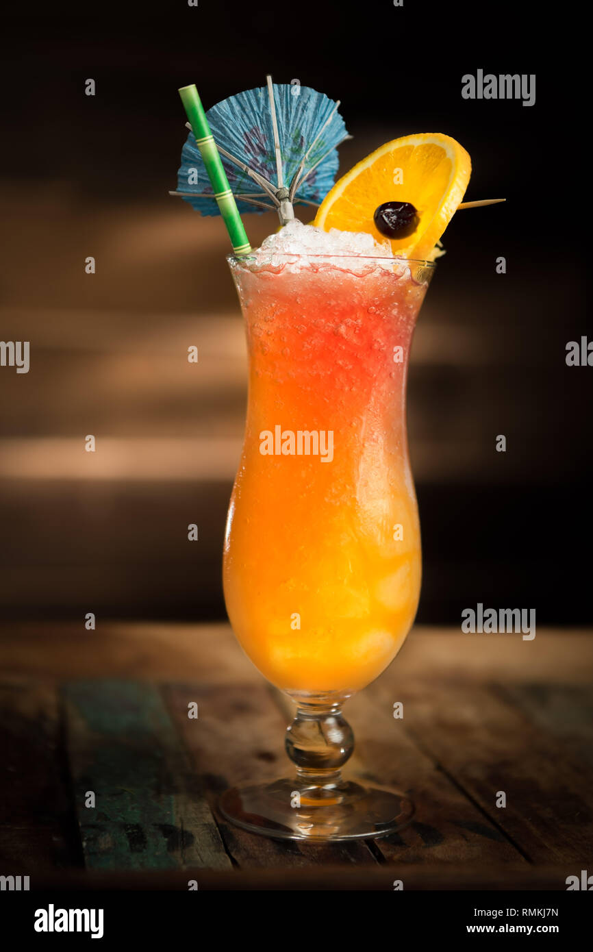 Tiki célébration cocktail servi dans un verre d'ouragan avec un parapluie, une cerise et une orange. Banque D'Images