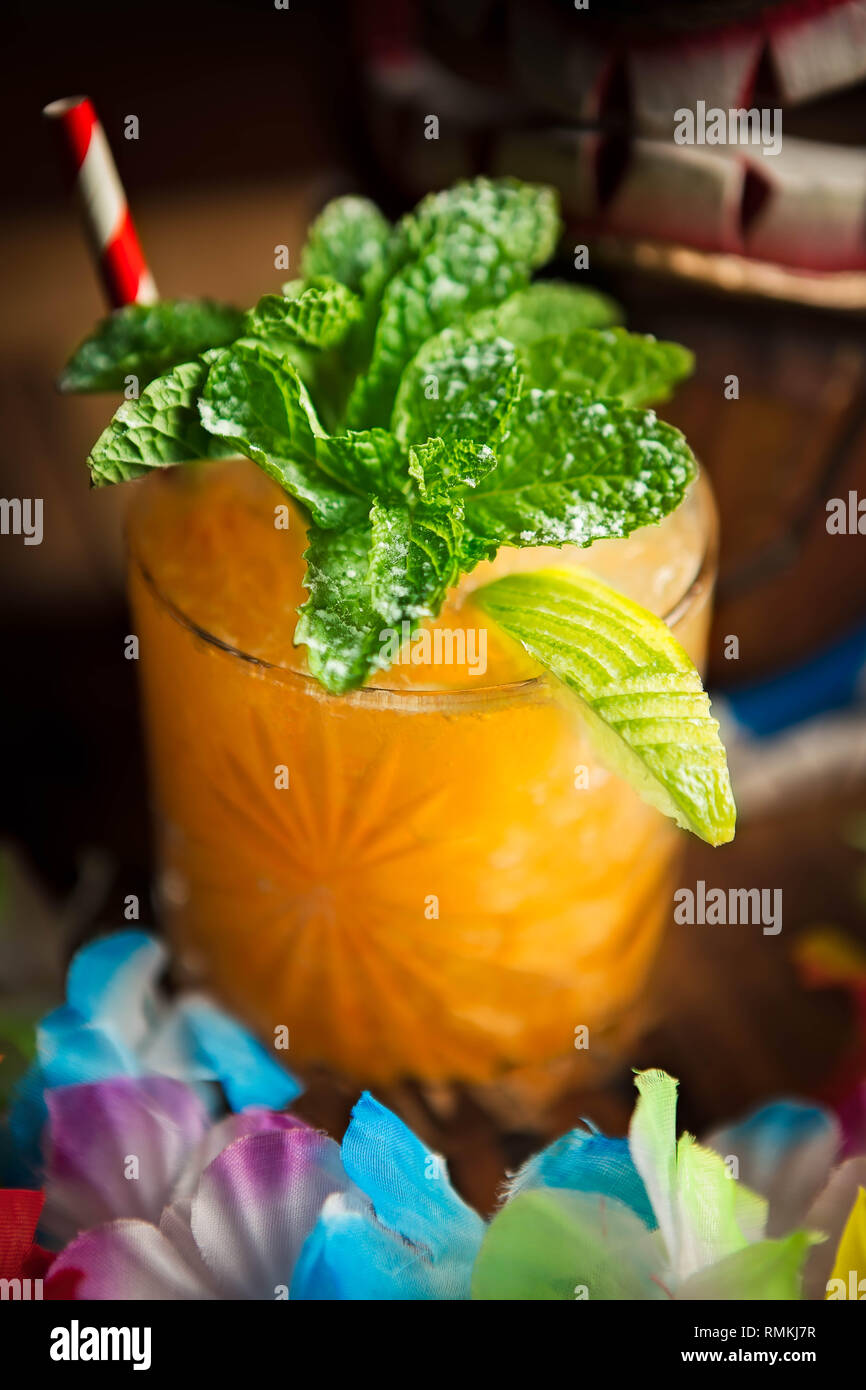 Tiki célébration cocktail servi dans un verre avec une roche et une lime fantaisie garnir de menthe Banque D'Images