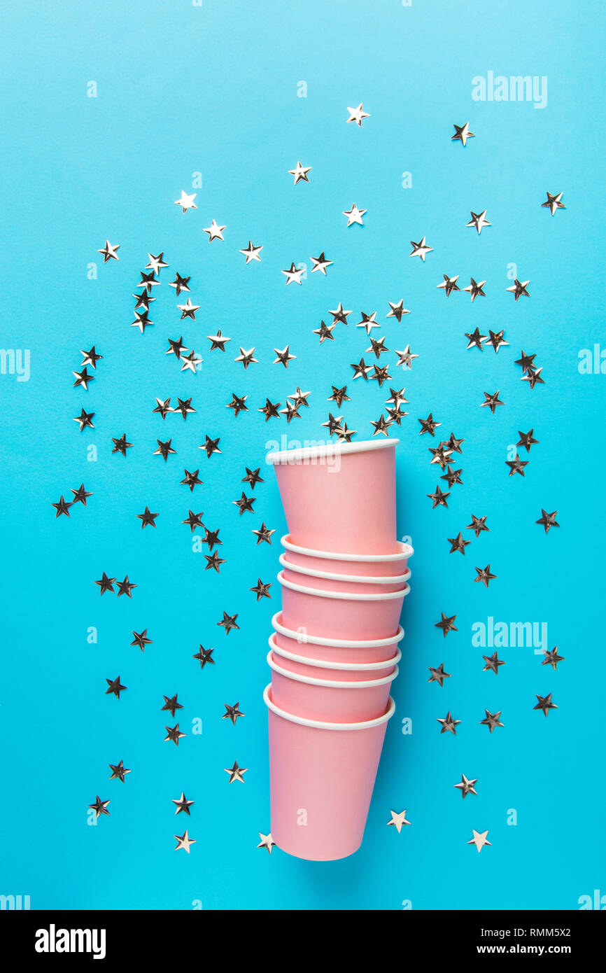 Pile de papier potable rose tasses sur fond bleu menthe forme étoile scintillante de confettis. Anniversaire fête vacances kids fun concept.Poster b Banque D'Images