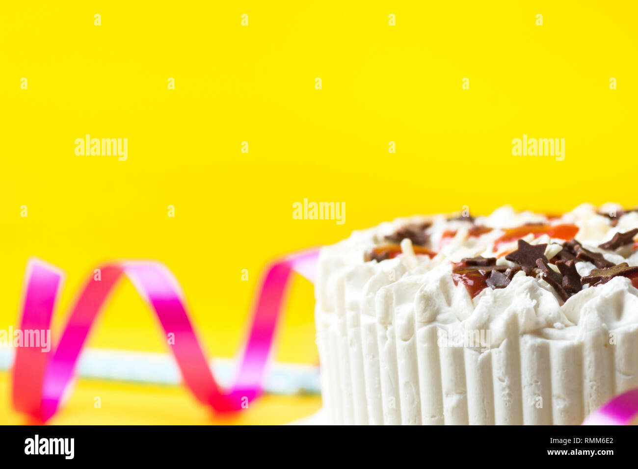 Couche éponge gâteau d'anniversaire avec de la crème chantilly au chocolat au lait glaçage star nutrifer confiture de fraises. Ruban bleu bouclés pailles sur jaune backg Banque D'Images