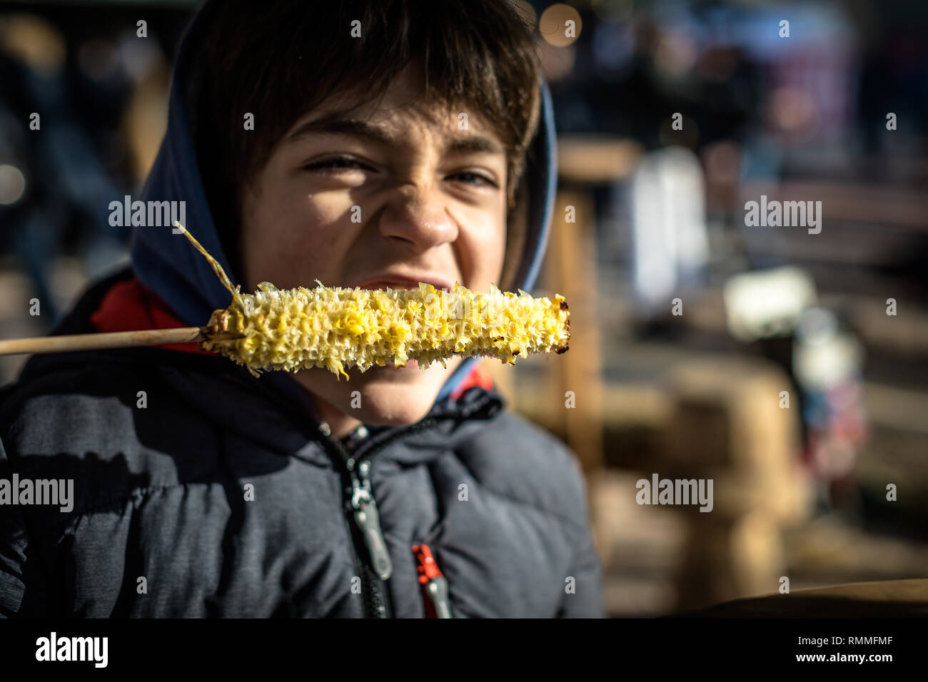 Boy eating corn on un s/n sur un bâton, Genève, Suisse Banque D'Images