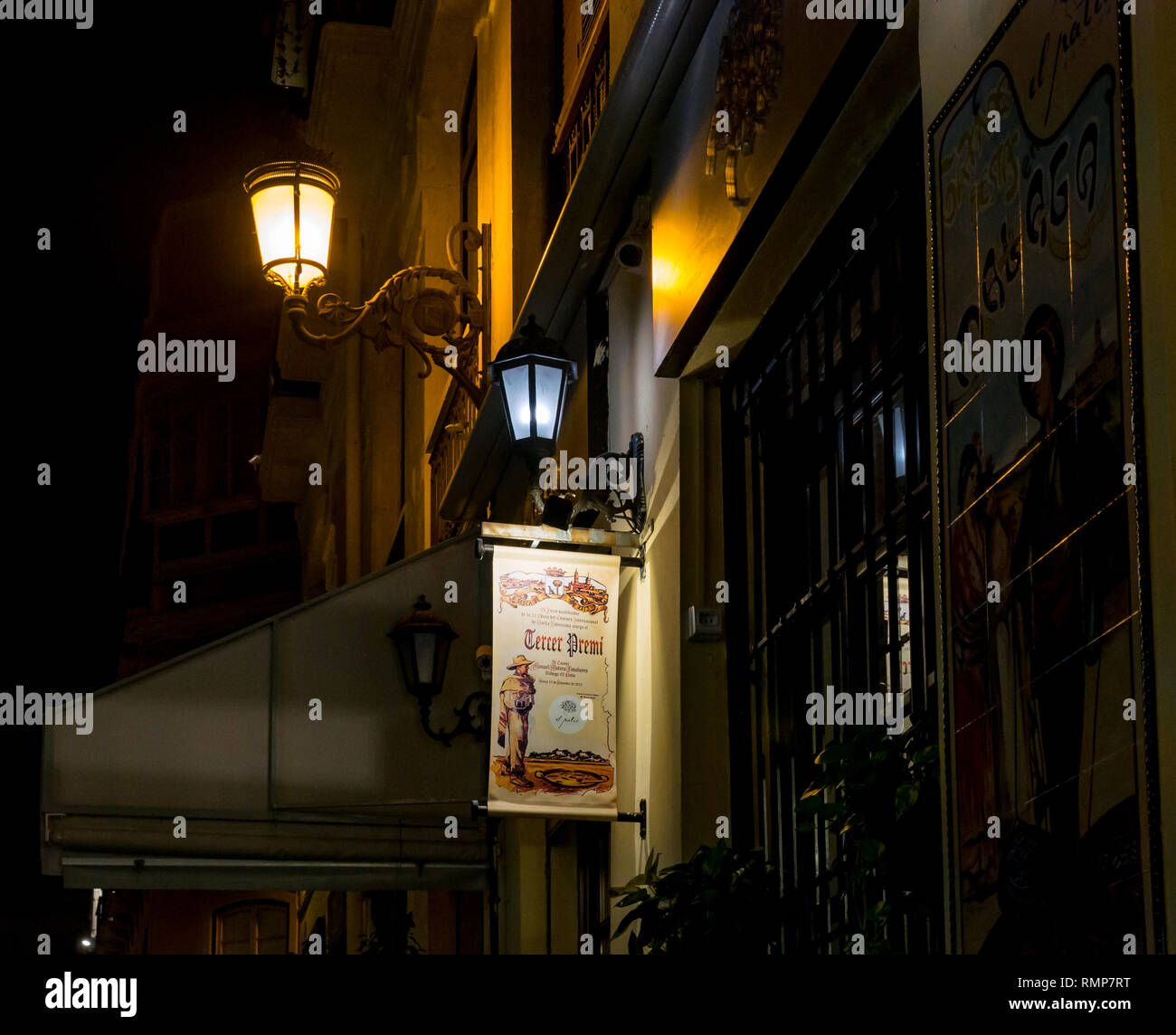 Hanging sign, vieux lampadaires et de mosaïques colorées, signe Bodega El Patio restaurant le soir, la vieille ville de Málaga, Andalousie, Espagne Banque D'Images