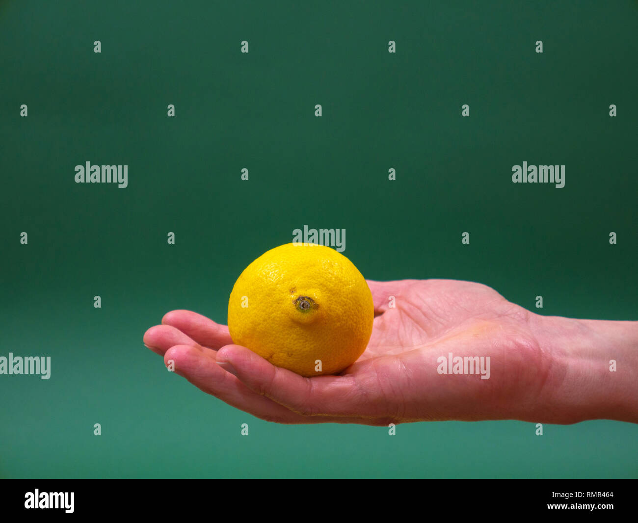 Citron dans mens Main sur fond vert isolement Banque D'Images